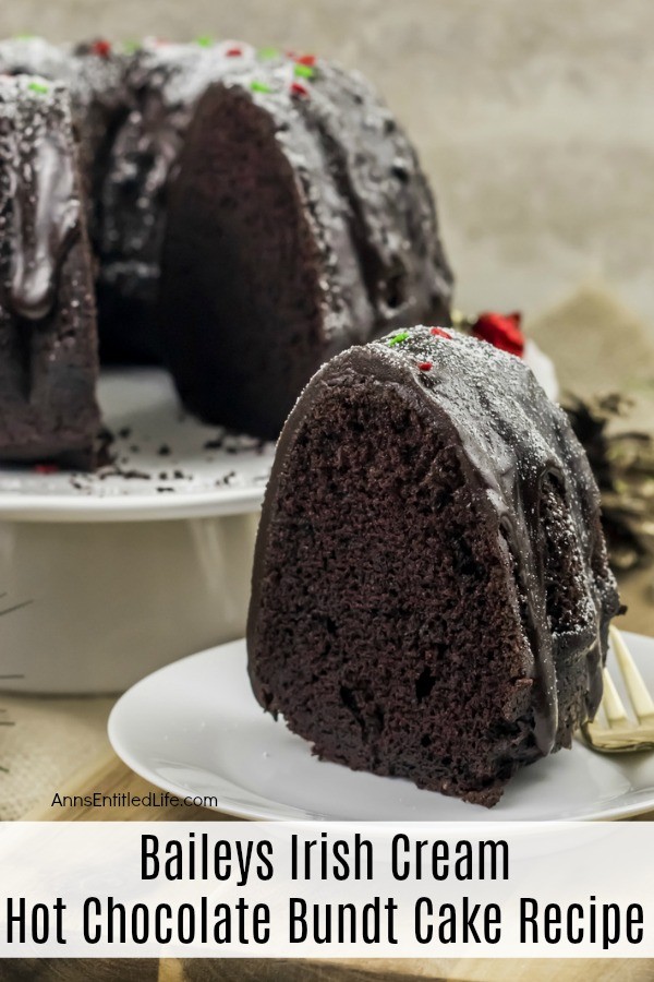 A slice of Baileys Irish Cream Hot Chocolate Bundt Cake sitting on a white plate. The remaining bundt cake is in the upper left. These are set upon a beige placemat.