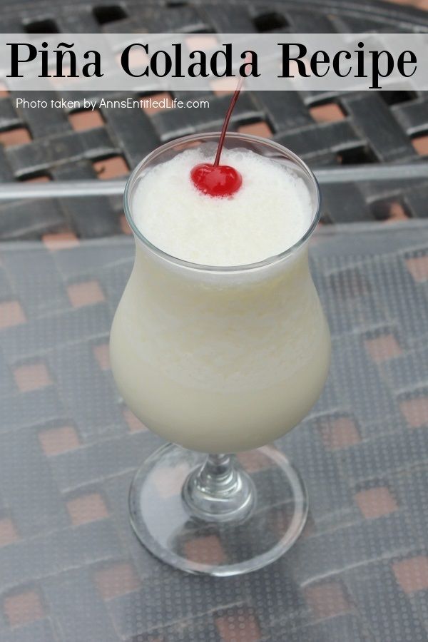 A single pina colada cocktail on a clear tray set atop an outdoor table in a backyard