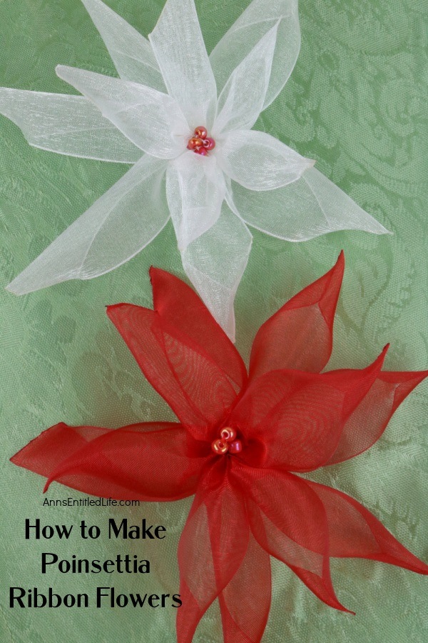 Two ribbon poinsettia flowers, one white on top, the other red below it, sit on a green background