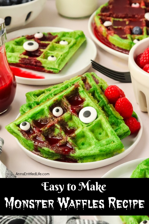 A stack of green waffles cut into triangles drenched in red syrup on a white plate. The waffles are topped with berries and candy eyes, and a fork is descending into the pile.