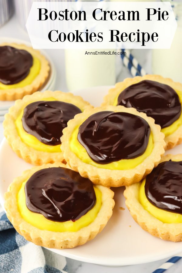 Five Boston cream pie cookies on a wire baking rack. There is a sixth cookie on a white plate in the upper left.