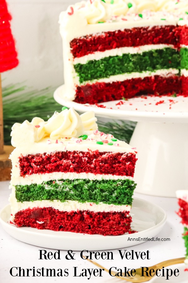 A piece of red and green velvet Christmas cake on a white plate, the rest of the cake is on a white cake stand behind it