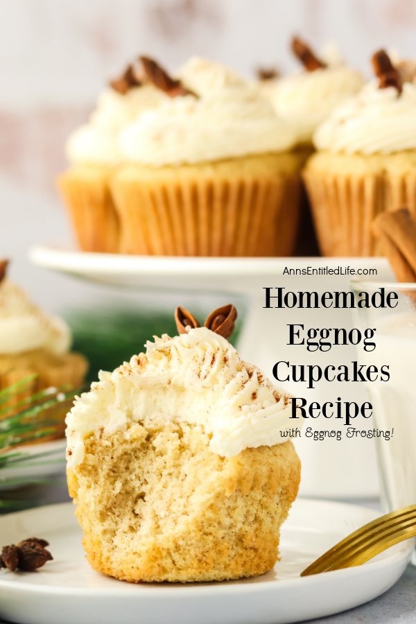 Ann eggnog cupcake on a white plate with a bite removed,  more are on a cake stand behind the plate.