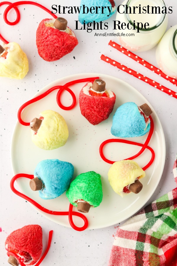 Overhead view of strawberries on a white plate which are decorated with chocolate and colored sugars to look like vintage Christmas lights