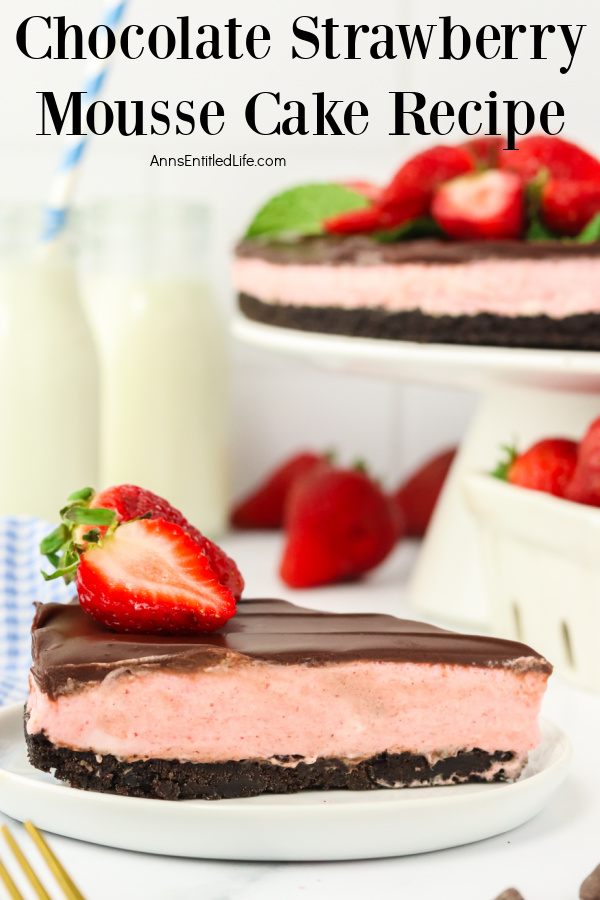 A slice of Homemade Chocolate Strawberry Mousse Cake sits in profile on a white cake. The remainder of the cake is in the upper right on a white cake stand, a few fresh strawberries are set below the stand