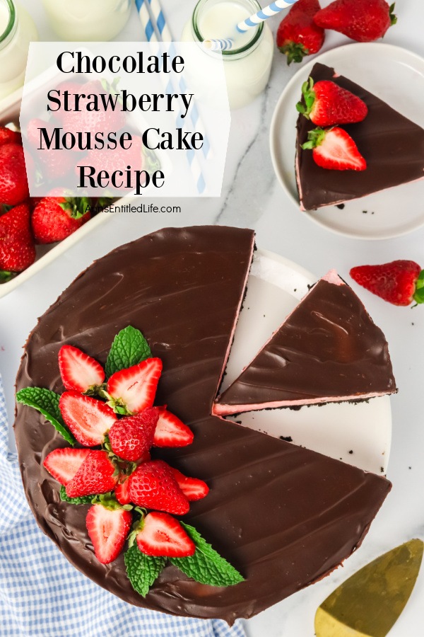 Overhead view of a Homemade Chocolate Strawberry Mousse Cake cut into pieces. There is a pint of fresh strawberries in the upper left, a slice of the mousse cake on a white plate in the upper right.